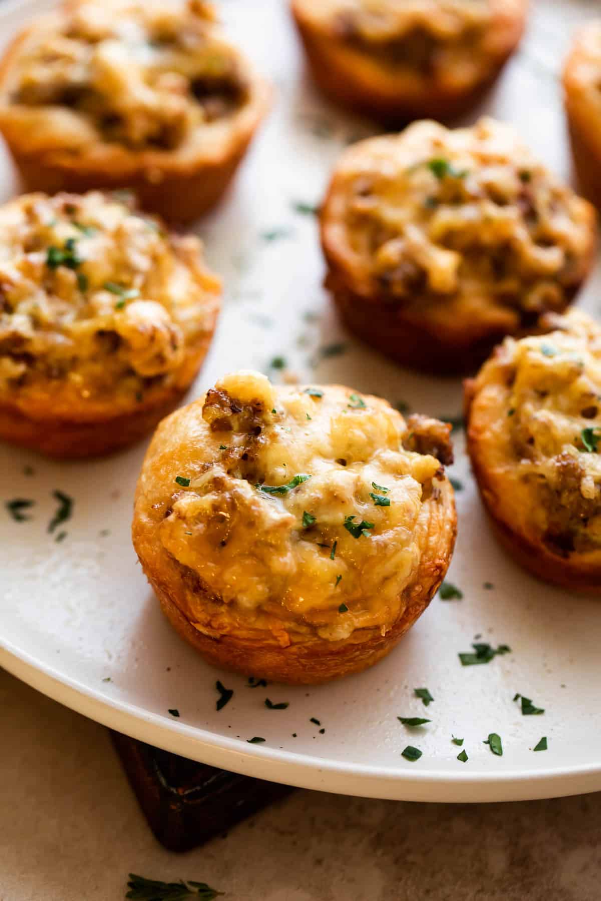 sausage breakfast cups arranged on a light plate and garnished with chopped parsley