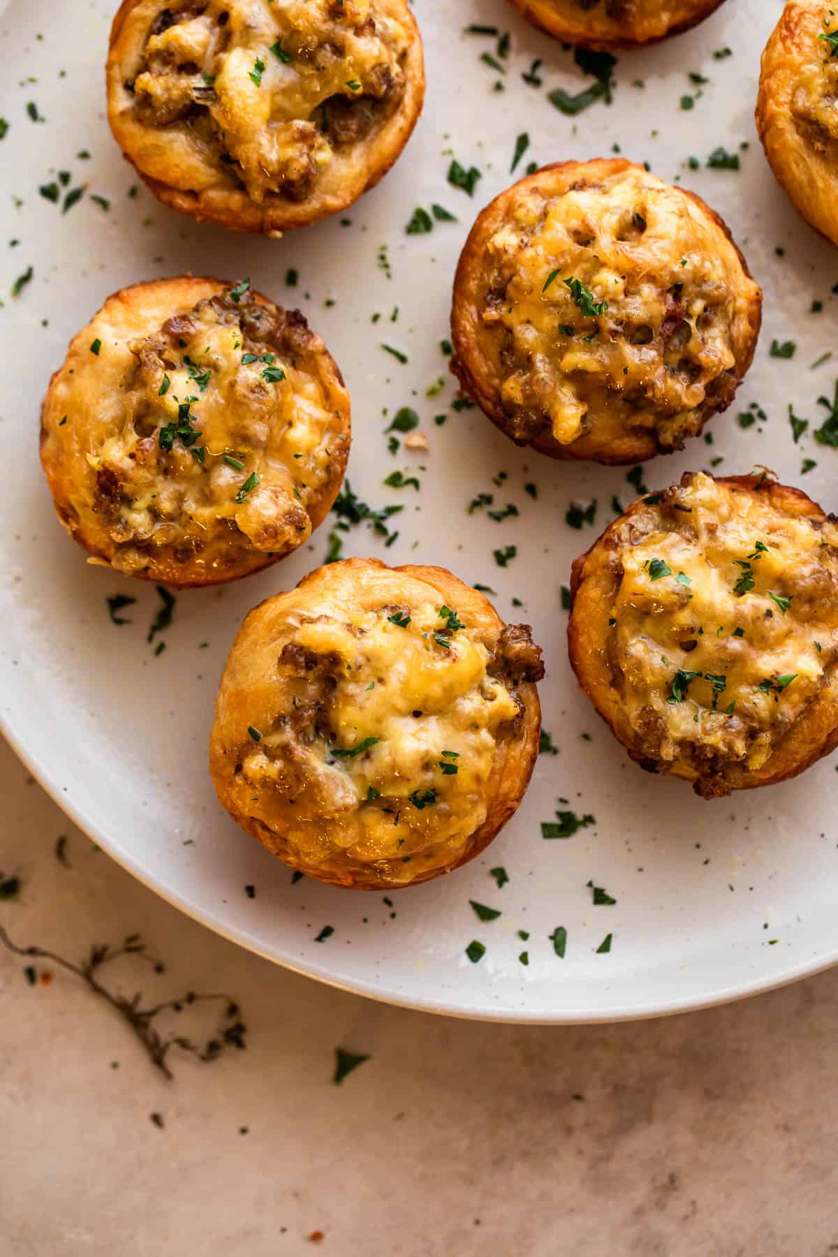 overhead shot of sausage breakfast cups arranged on a light plate and garnished with chopped parsley