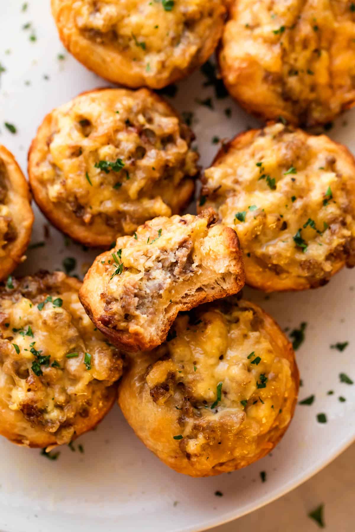 overhead shot of sausage breakfast cups arranged on a light plate and garnished with chopped parsley