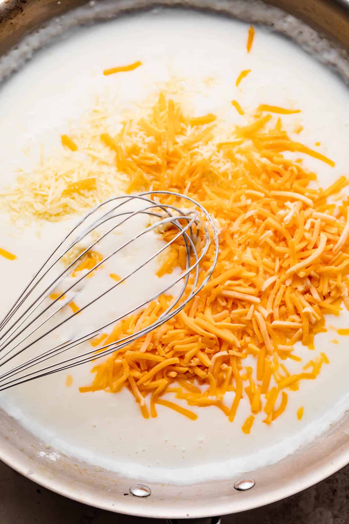 whisking shredded cheddar cheese with milk.