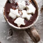 overhead shot of hot chocolate in a brown mug and topped with star shaped marshmallows