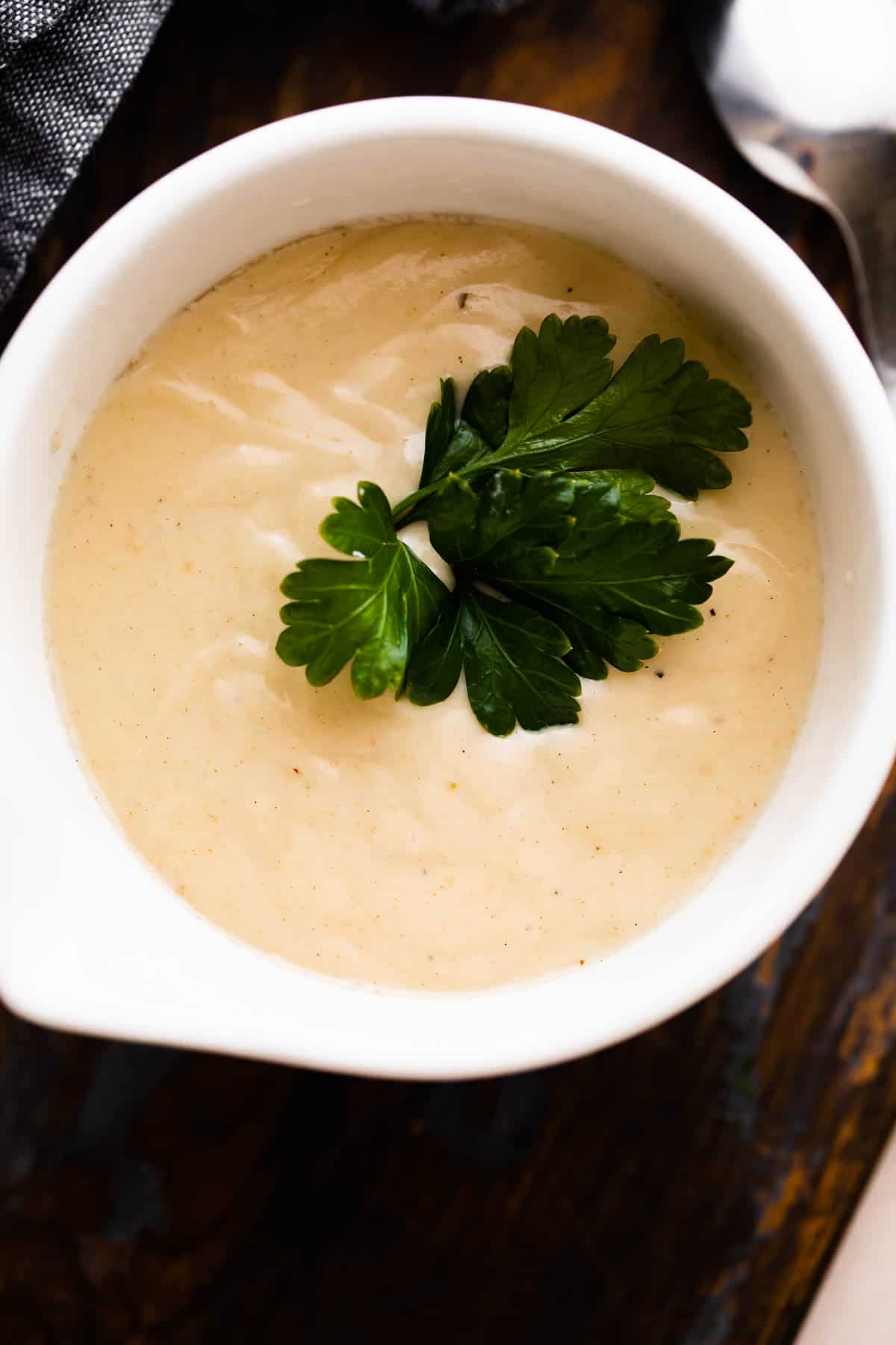 overhead shot of a white ceramic cup filled with homemade cream of chicken soup