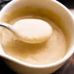 overhead shot of a white ceramic cup filled with homemade cream of chicken soup and a spoon scooping out the soup.