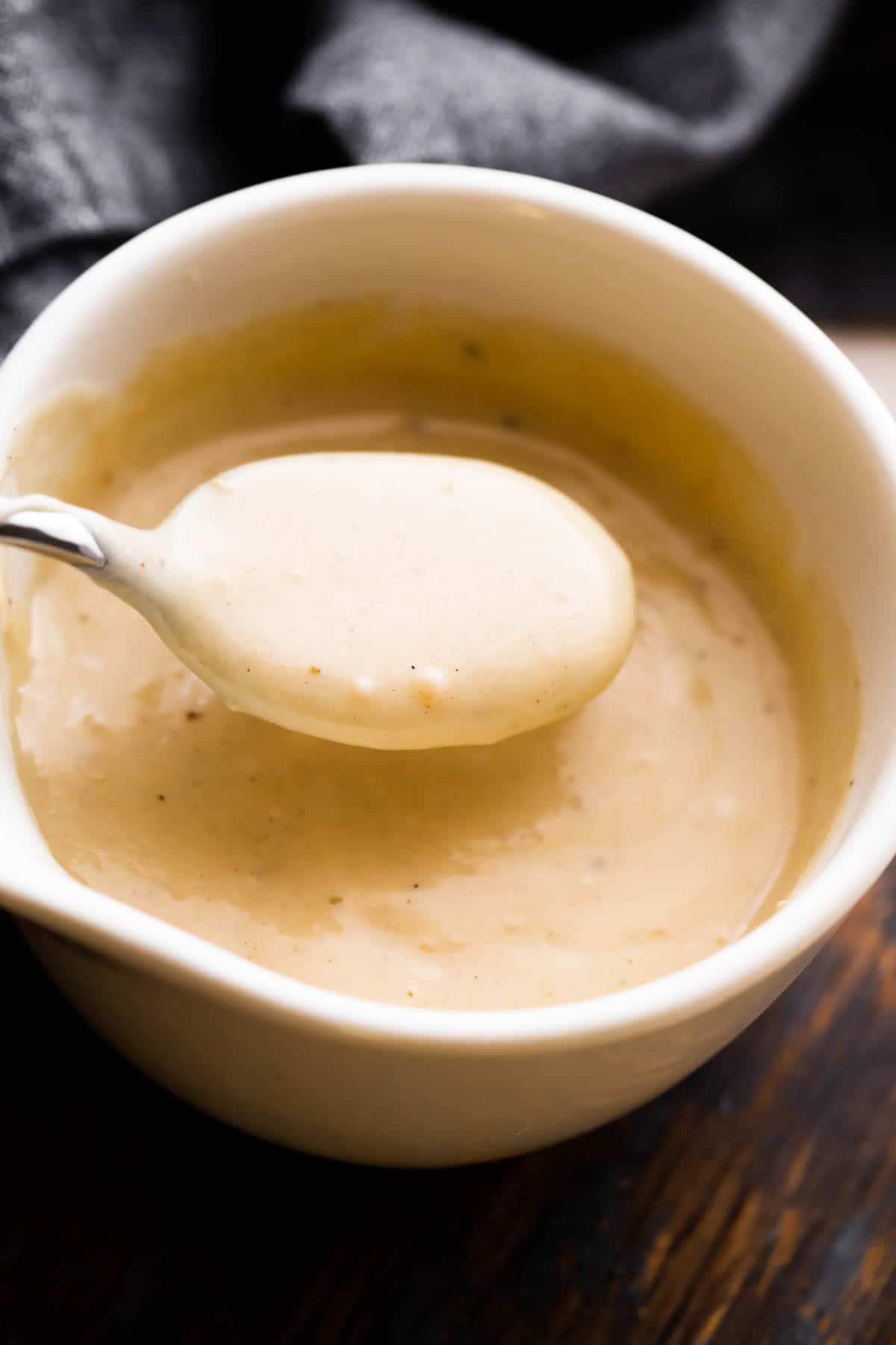 overhead shot of a white ceramic cup filled with homemade cream of chicken soup and a spoon scooping out the soup.