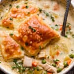 overhead shot of a cream colored bowl filled with turkey pot pie soup and topped with a piece of puff pastry square.