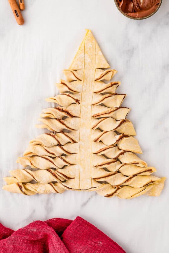 The unbaked puff pastry tree, with the horizontal strips twisted to show the filling.