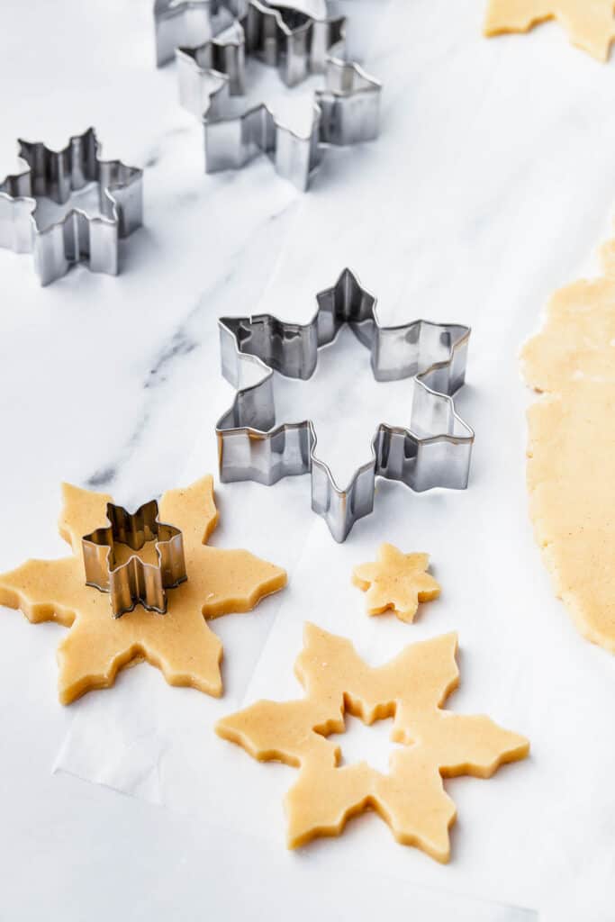 Cut out snowflake-shaped cookies on a work surface.