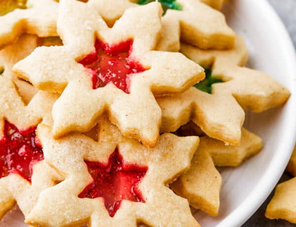 Snowflake-shaped sugar cookies with red and green centers on a round white plate.