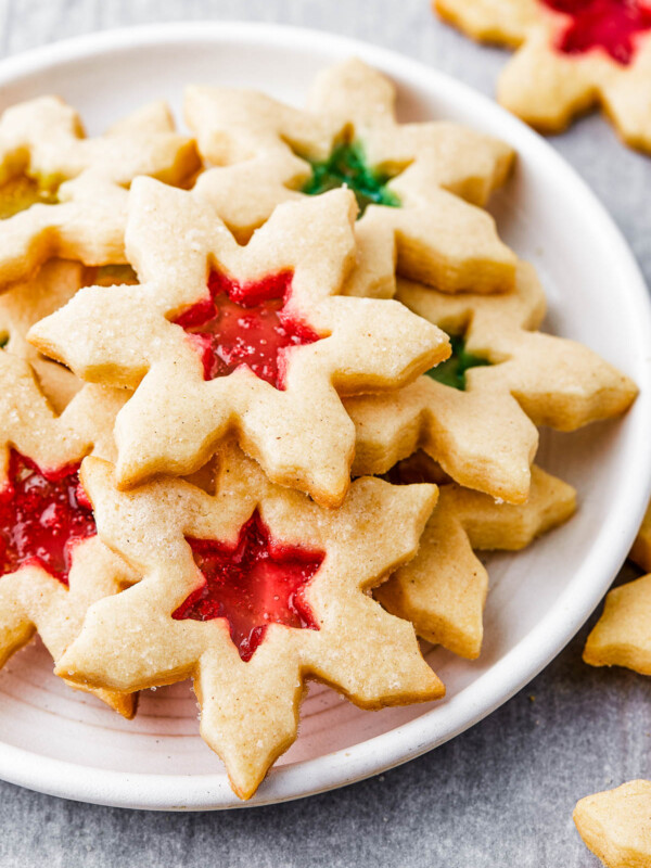 Snowflake-shaped sugar cookies with red and green centers on a round white plate.