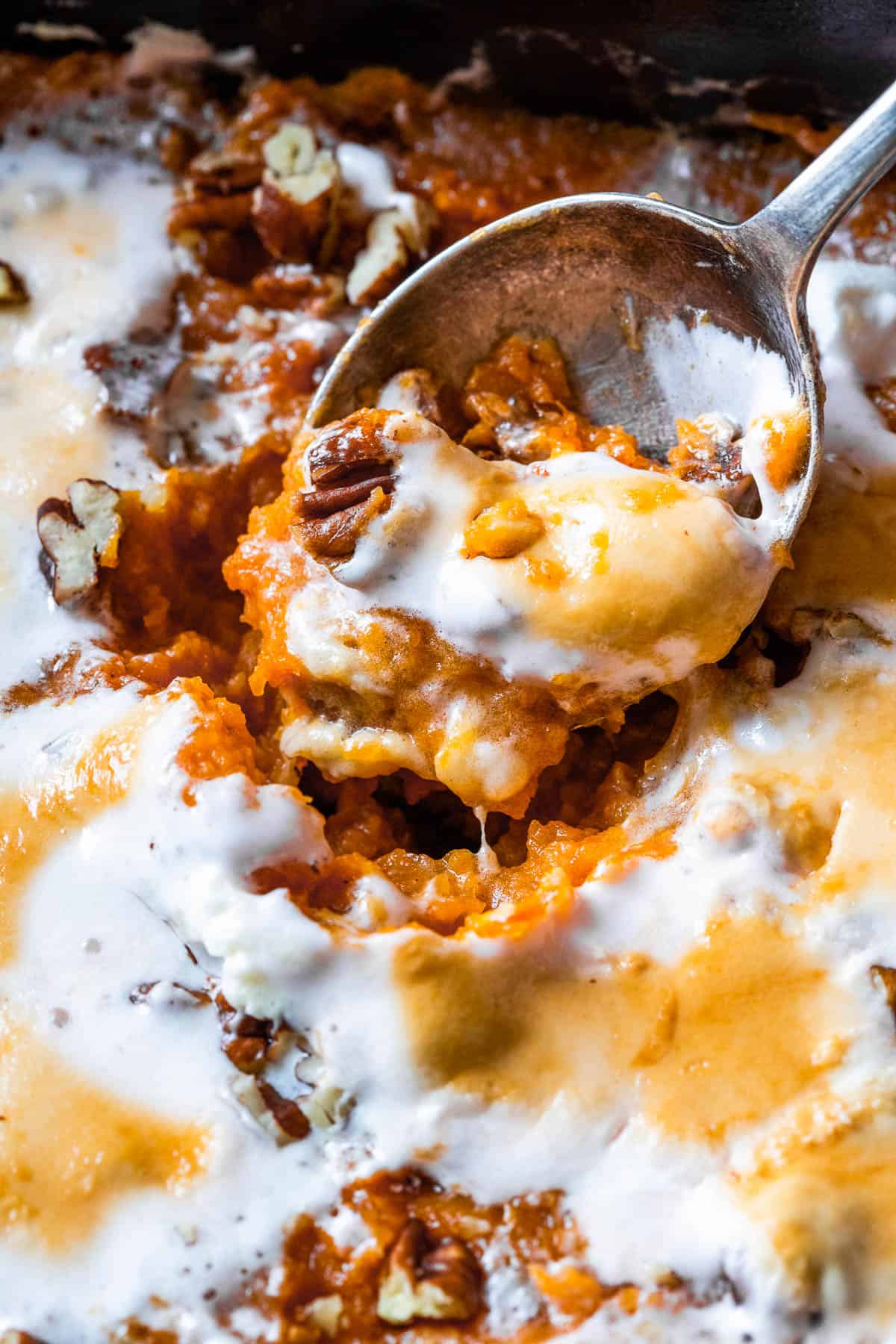 A close up shot of sweet potato casserole, showing the texture of the casserole mixture and melted marshmallow topping.