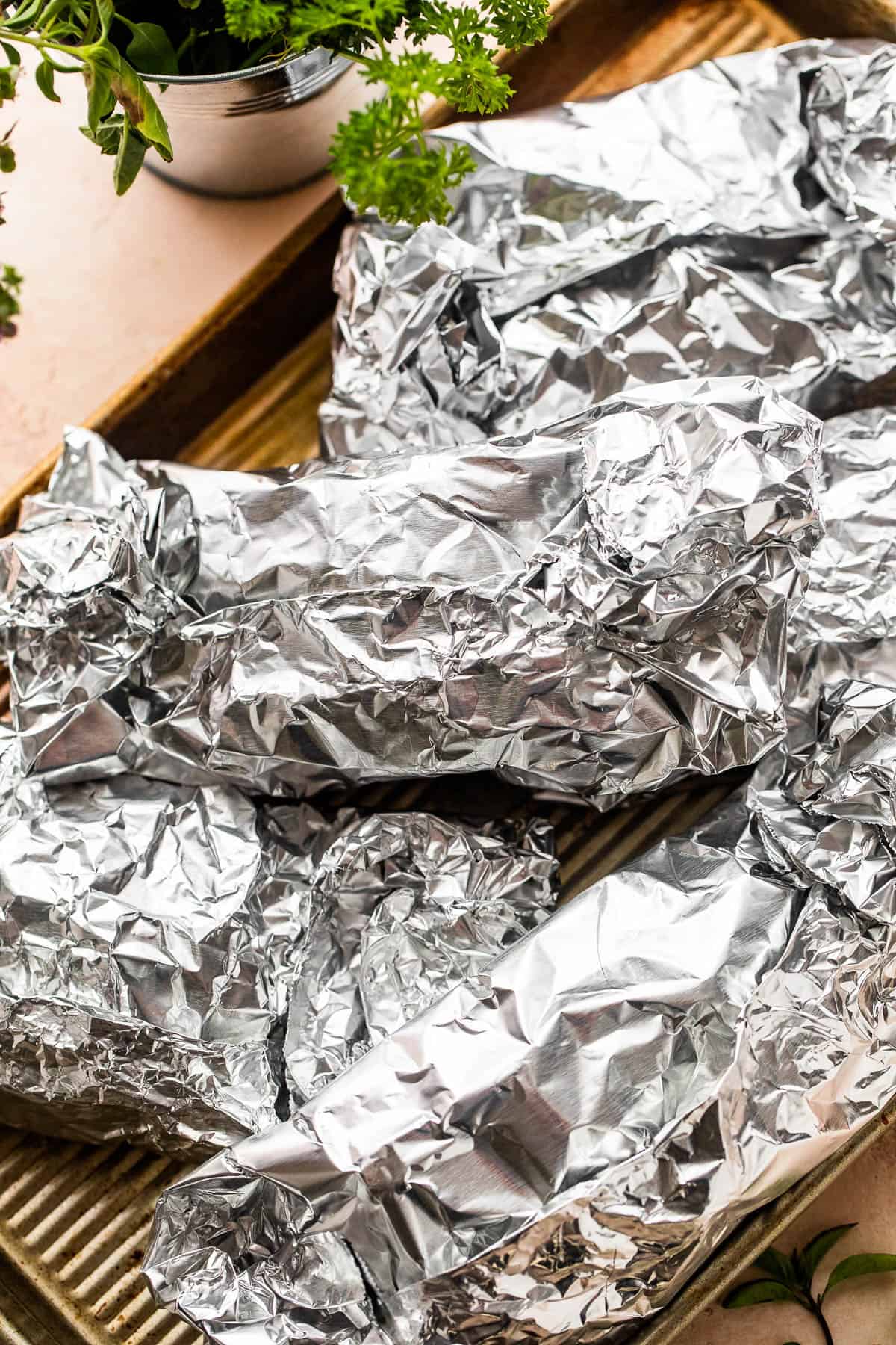 several foil packets arranged on a baking sheet.