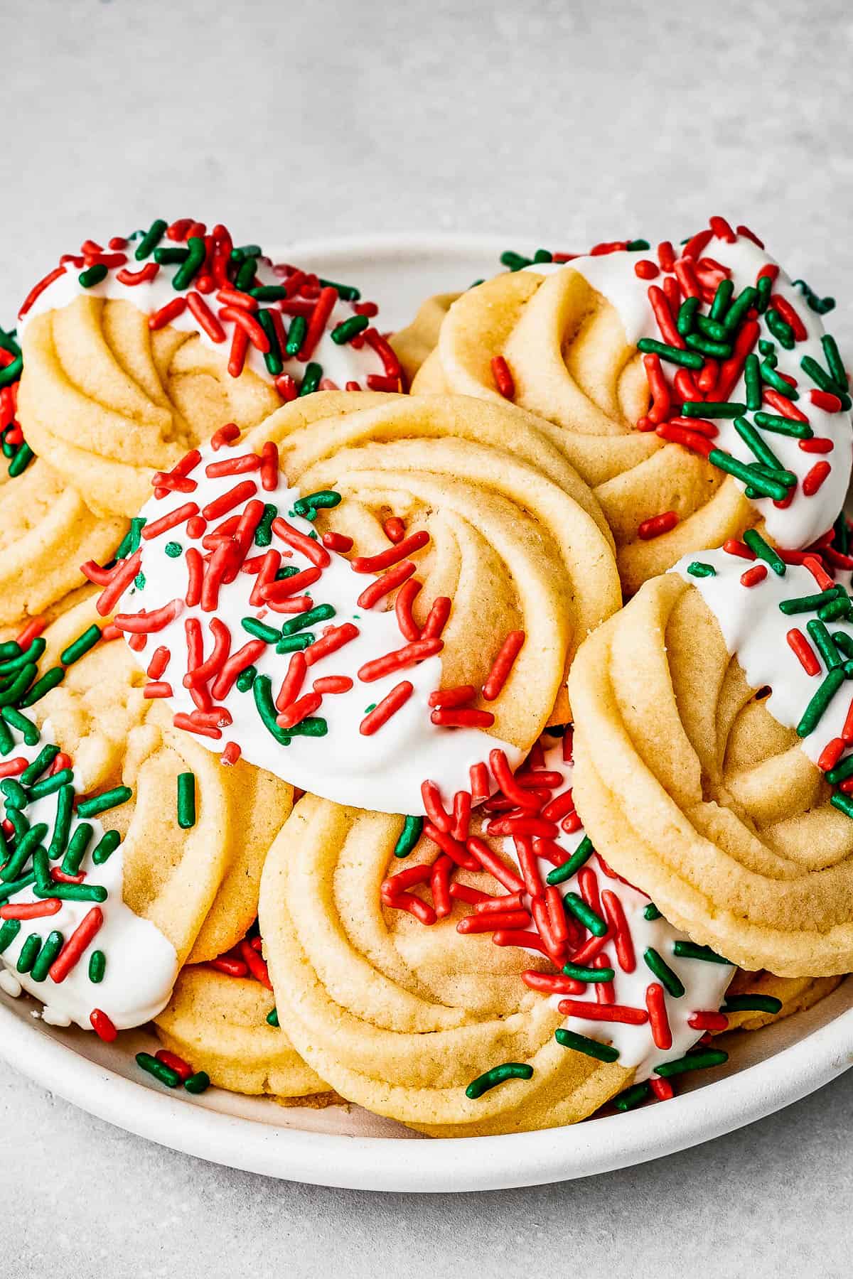 Butter cookies decorated with white chocolate and red and green sprinkles.
