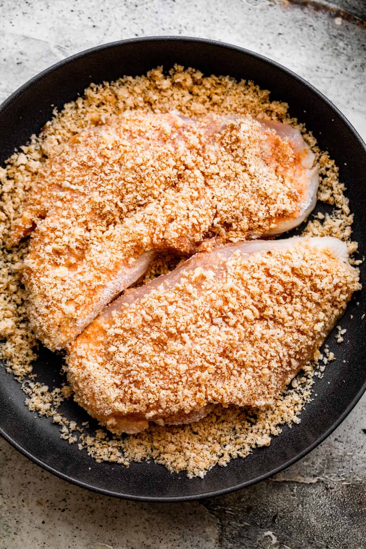 overhead shot of breaded chicken set on a black plate.