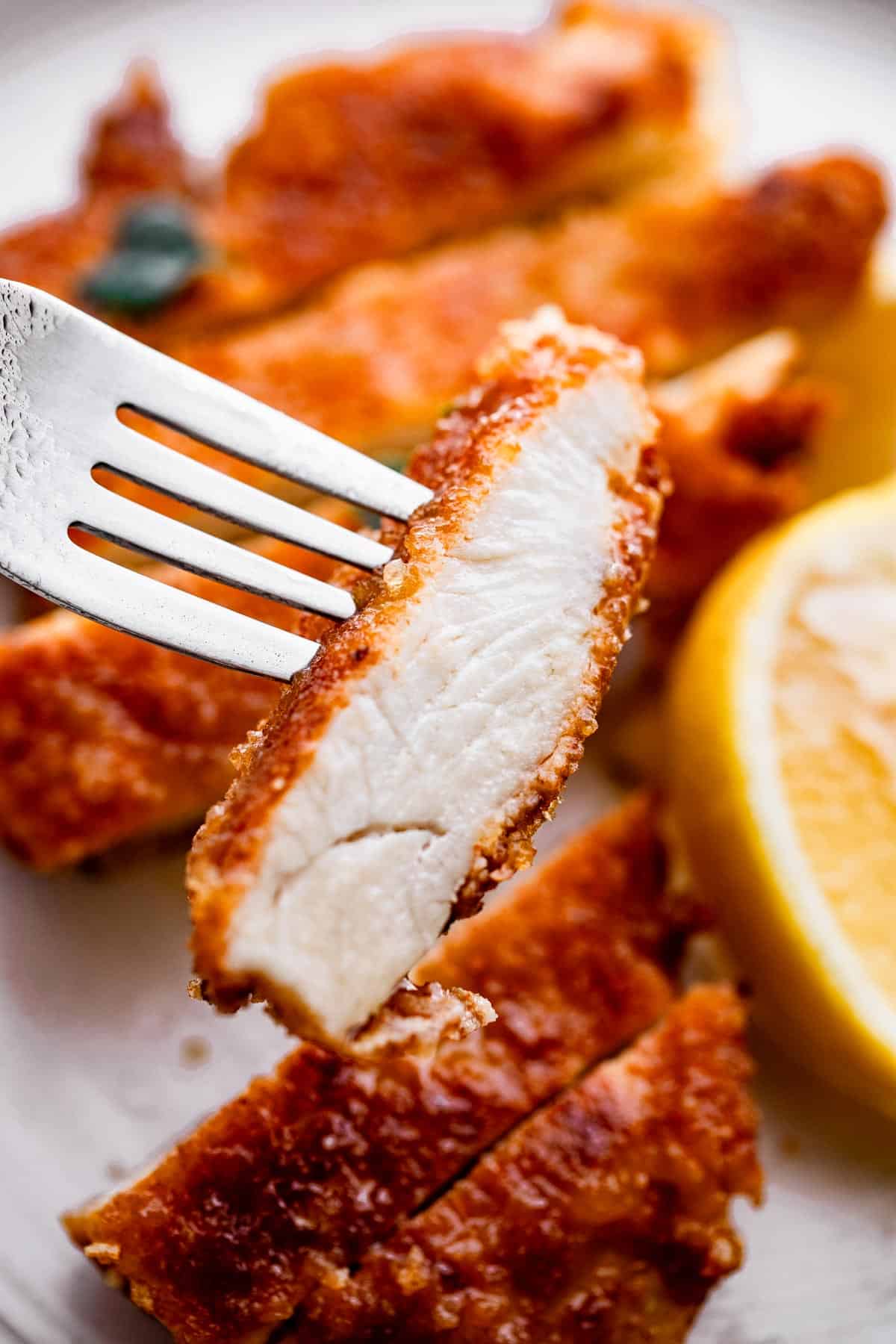 fork holding up a slice of chicken schnitzel