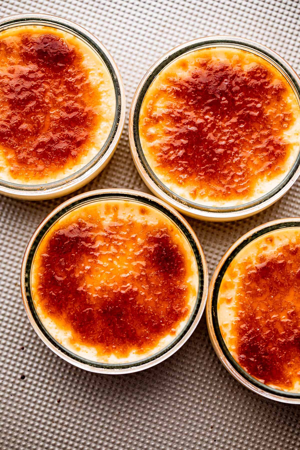 overhead shot of four small jars with creme brulee set on a silver colored background