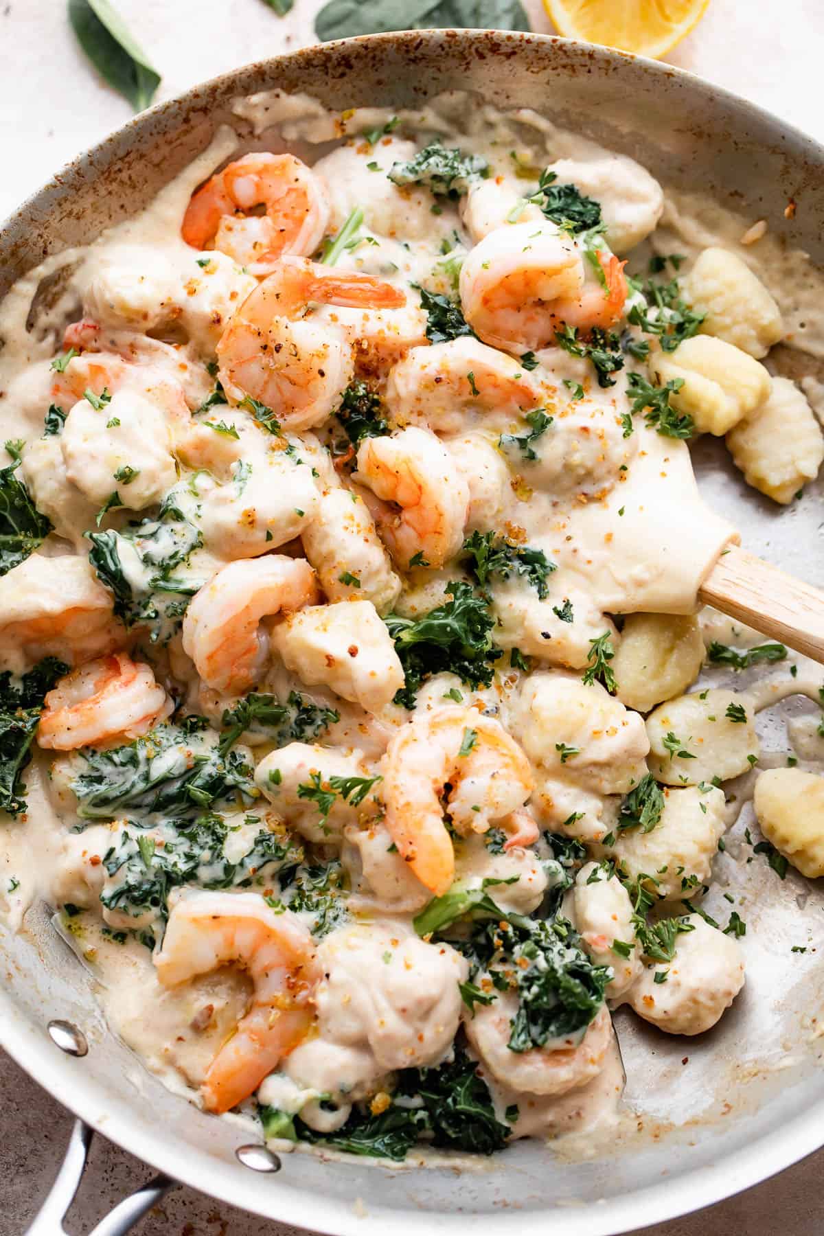 overhead shot of a steel skillet filled with gnocchi, shrimp, and greens.