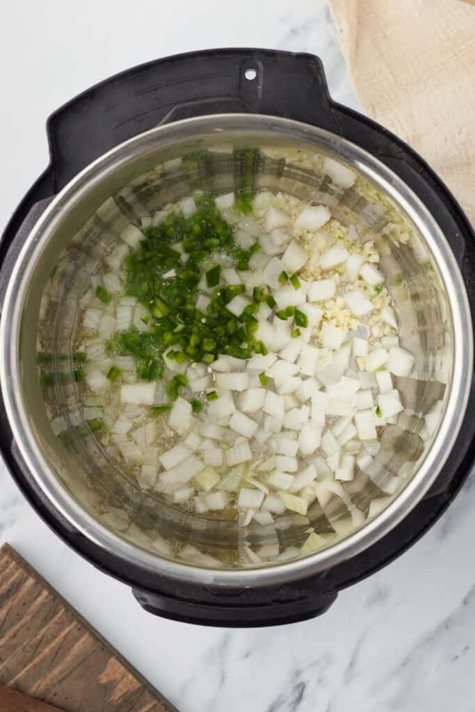 Overhead shot of an Instant Pot, with onions, garlic, and jalapeno inside.