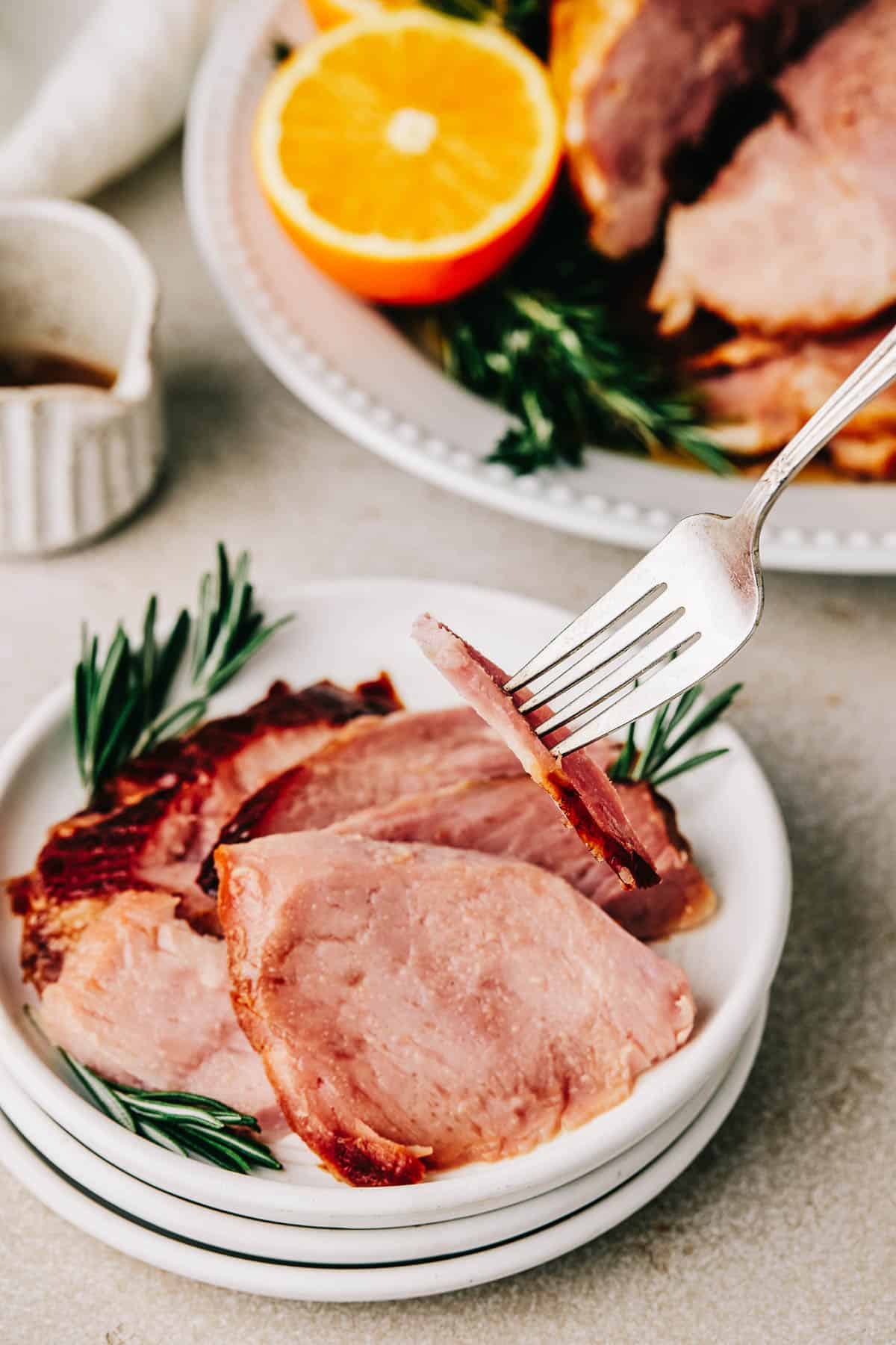 A fork lifting a slice of ham from a small plate.