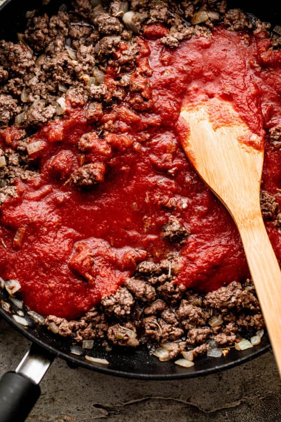 cooking ground beef with tomato sauce in a skillet.