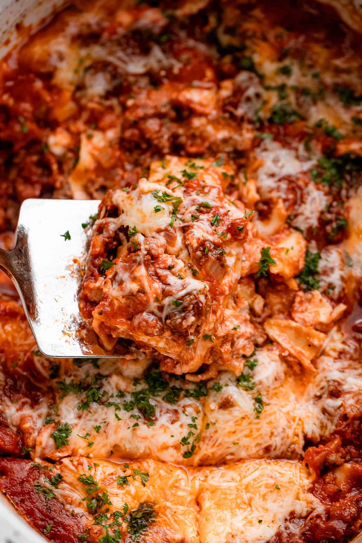 up close shot of a spatula lifting up a piece of lasagna from the slow cooker.