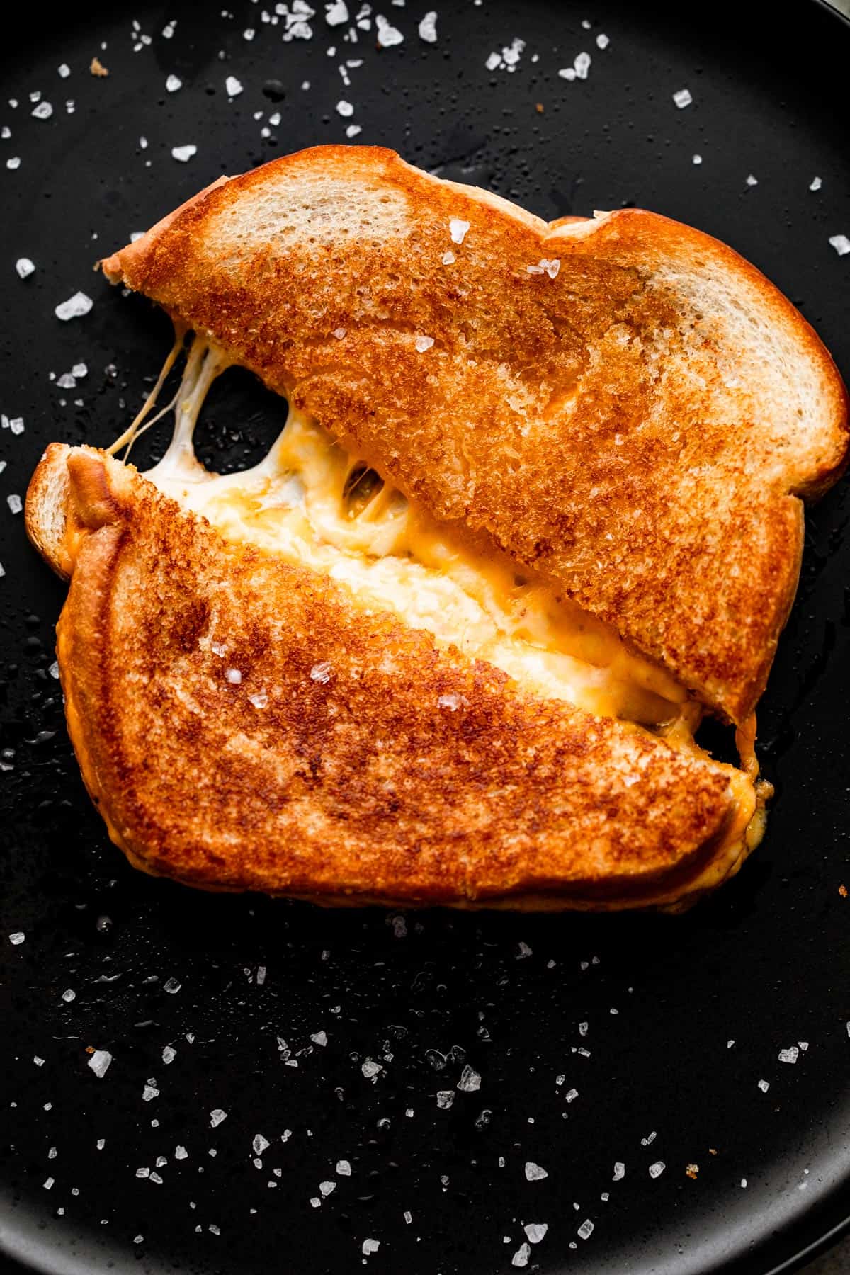 baked grilled cheese sandwich cut and pulled apart, with melted cheese tearing through the center.