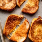 four baked grilled cheese sandwiches set on a baking sheet and diagonally cut in half.