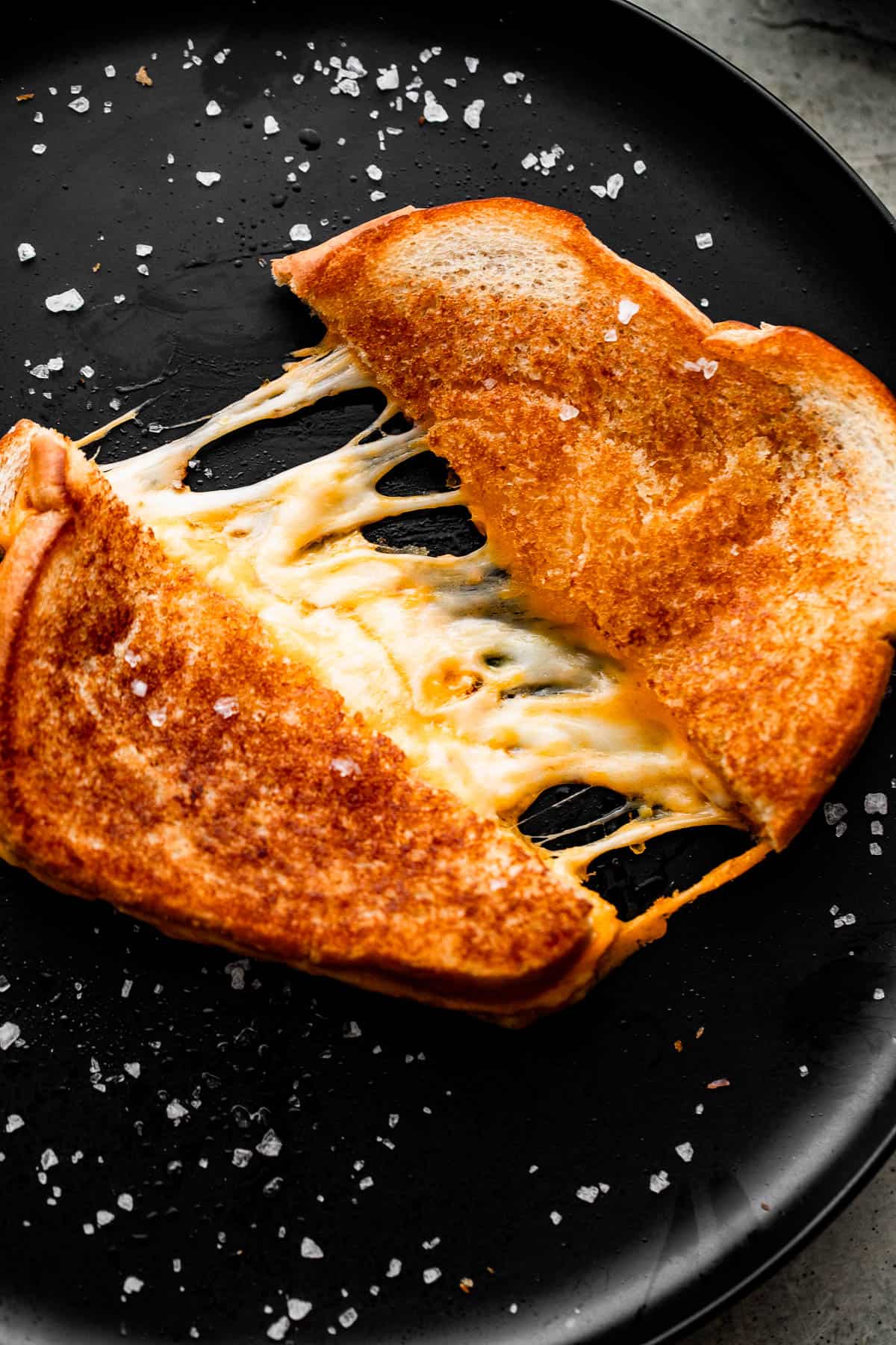 baked grilled cheese sandwich cut and pulled apart, with melted cheese tearing through the center.