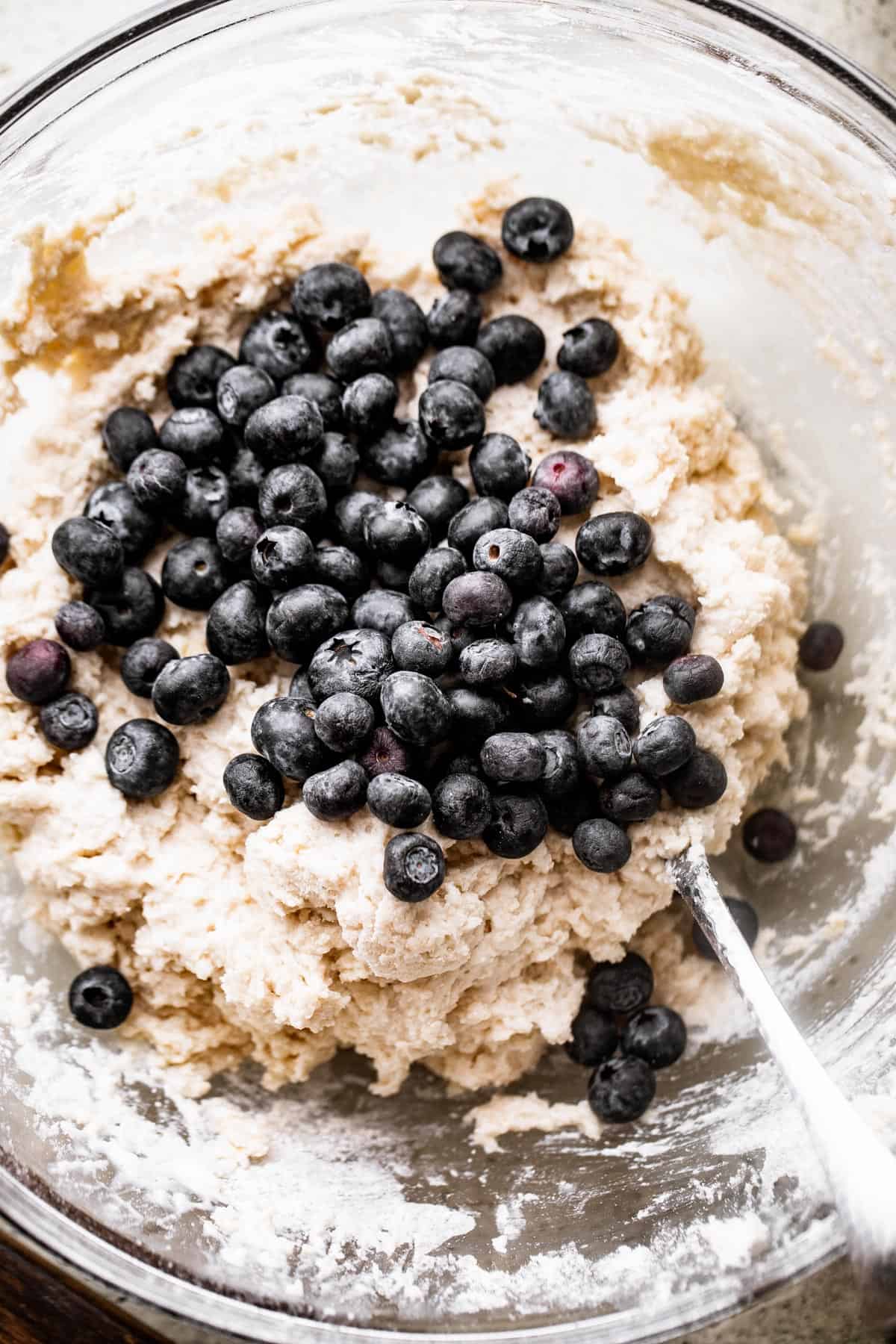 folding blueberries into a batter for blueberry scones