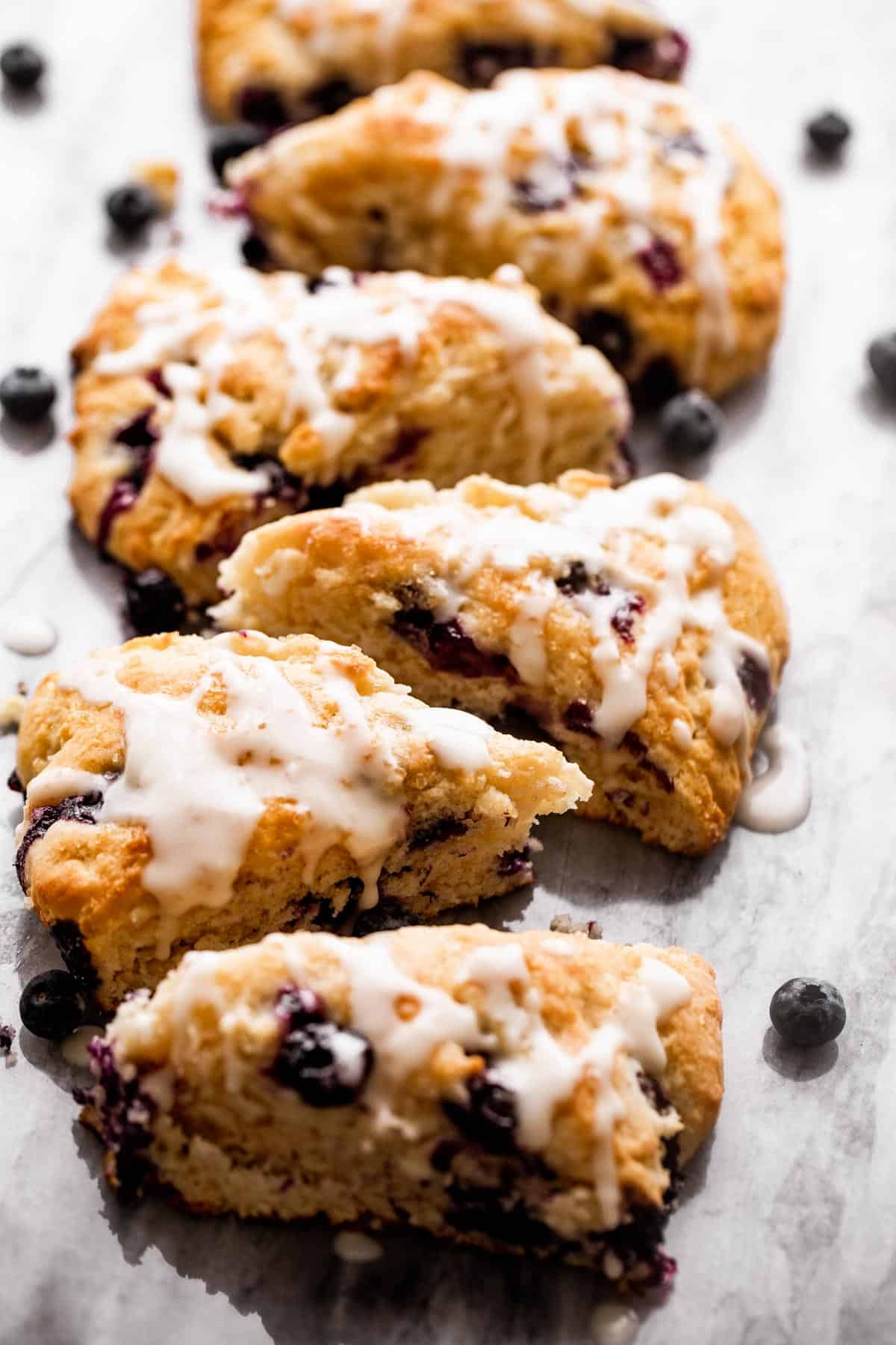 six blueberry scones arranged in a single row on a marble board