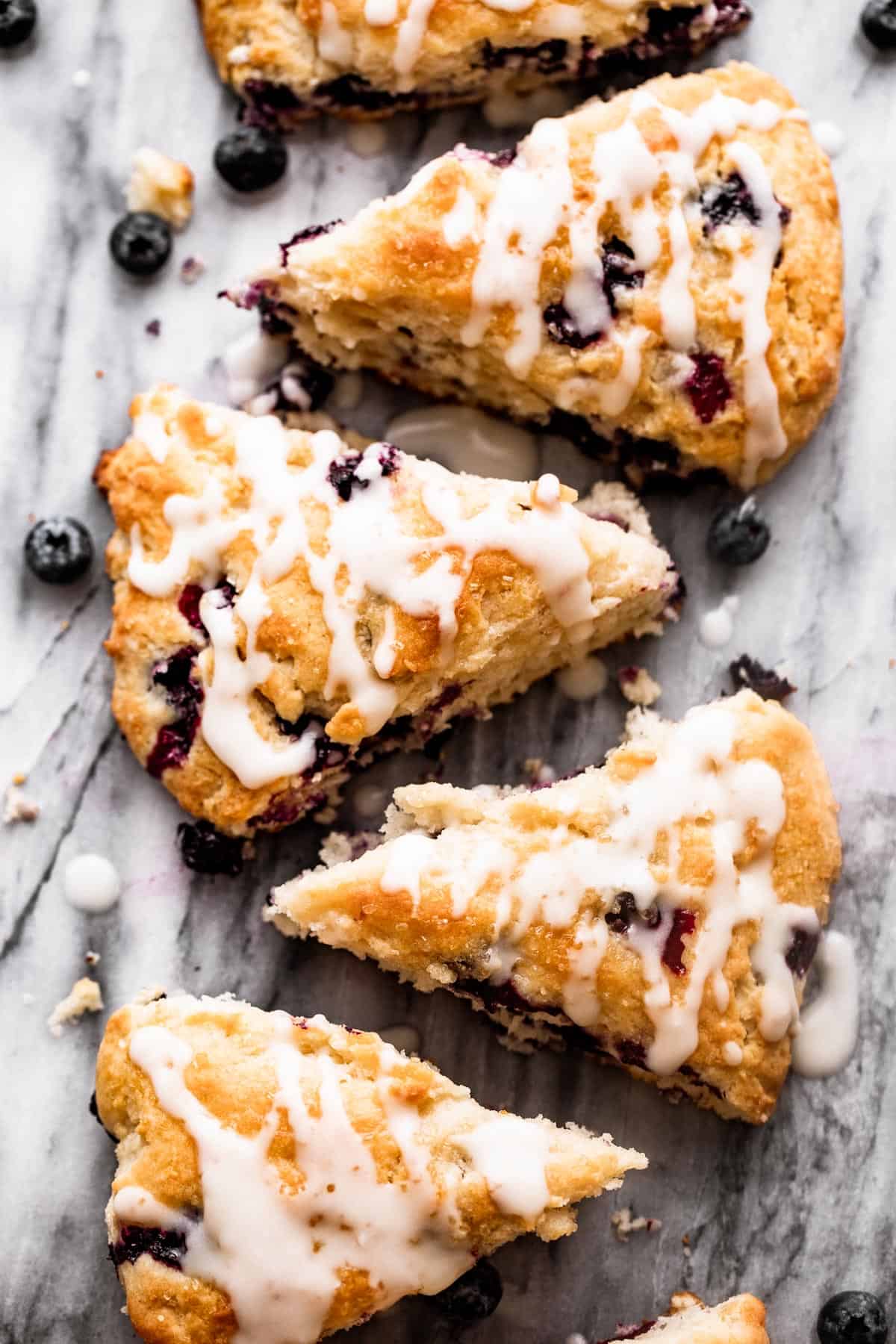overhead shot of blueberry scones arranged in a row on top of a marble slab
