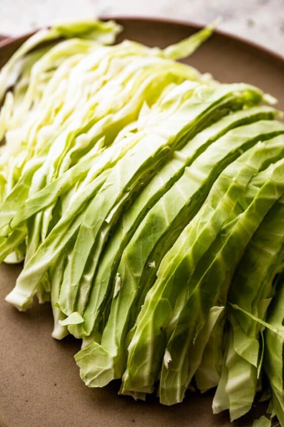 sliced green cabbage on a brown plate.