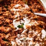 overhead shot of Cabbage Roll Casserole in a white baking dish, and the casserole is smothered with sour cream on top.