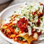 Close-up shot of three stuffed manicotti shells on a small plate.