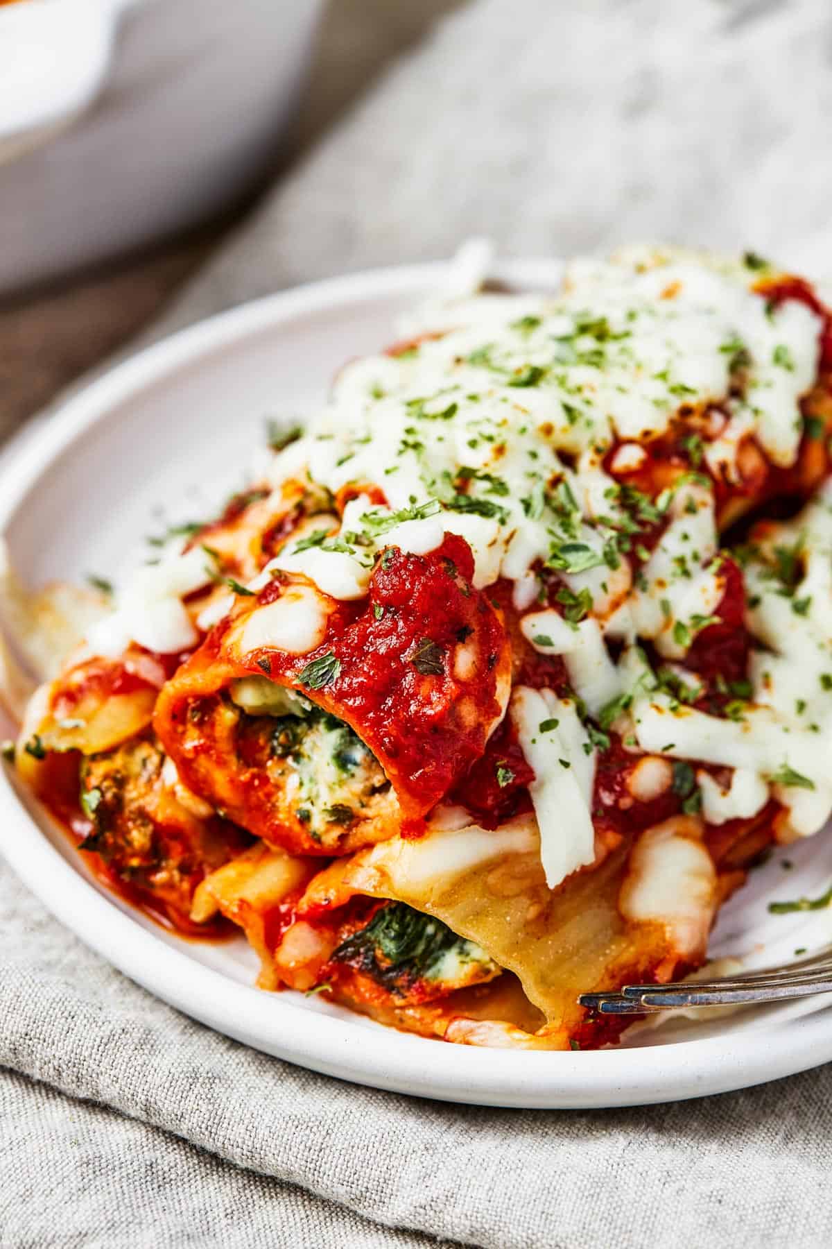 Close-up shot of three stuffed manicotti shells on a small plate.