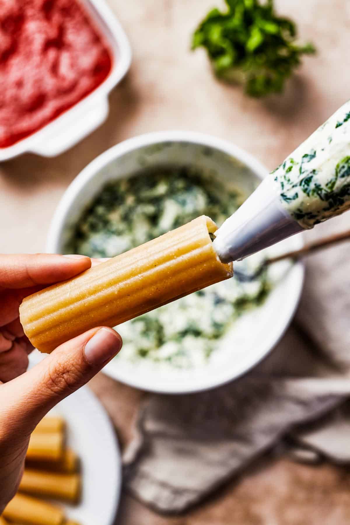 Filling being piped into a pasta shell.