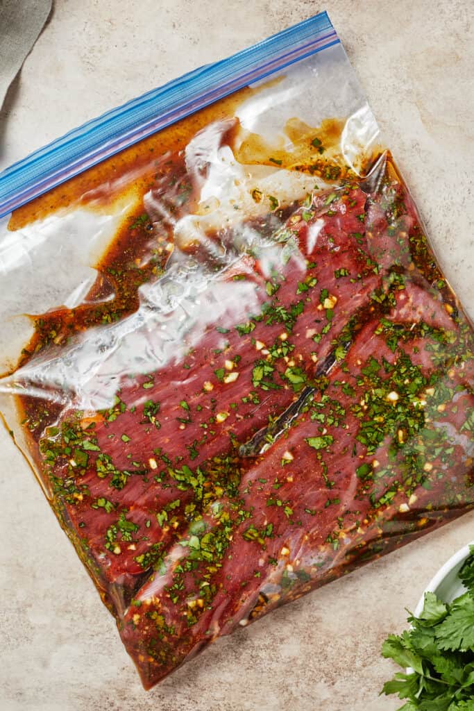 A zip-top bag with flank steak and marinade inside.