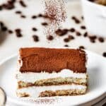 A square of tiramisu on a dessert plate, with the layers visible from the side.