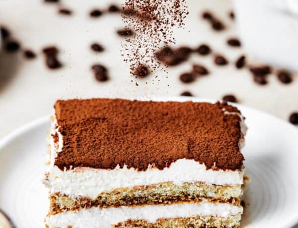 A square of tiramisu on a dessert plate, with the layers visible from the side.