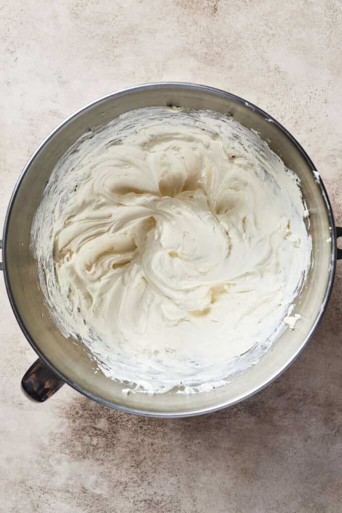 A metal mixing bowl filled with a creamy mixture.