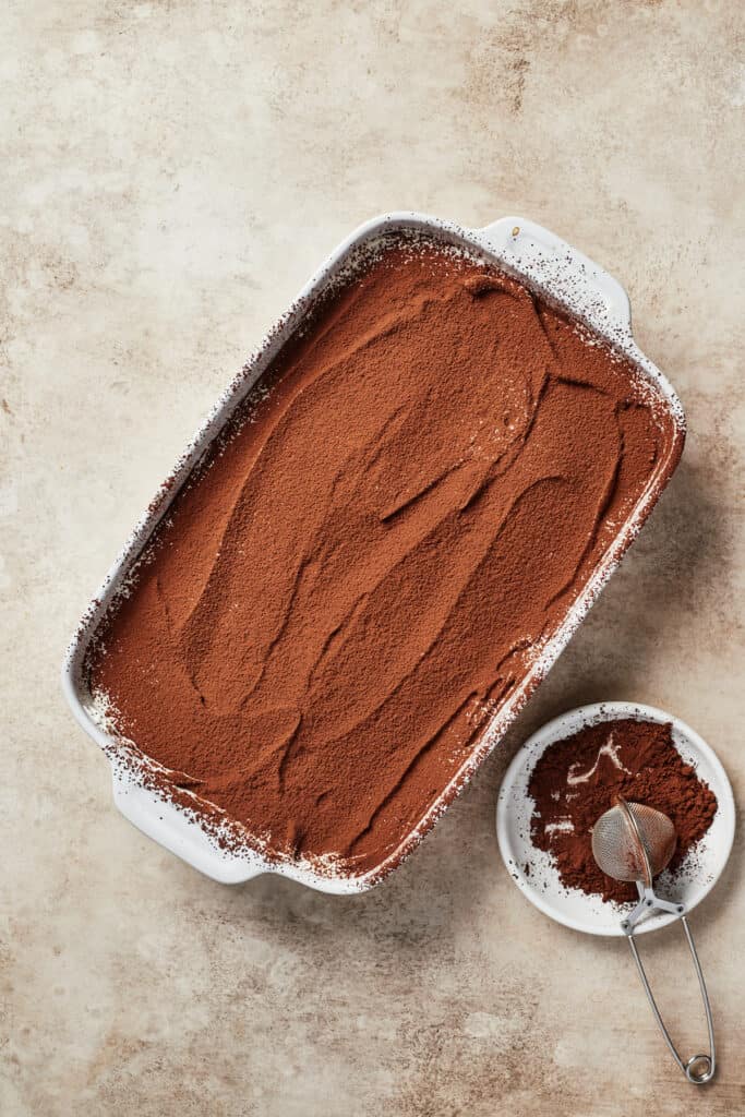 A baking dish with a cocoa-powder topped dessert.