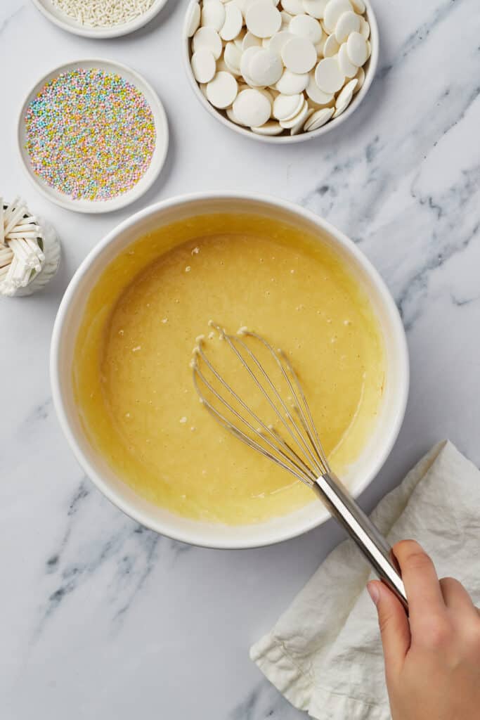 Yellow cake batter in a mixing bowl with a whisk.