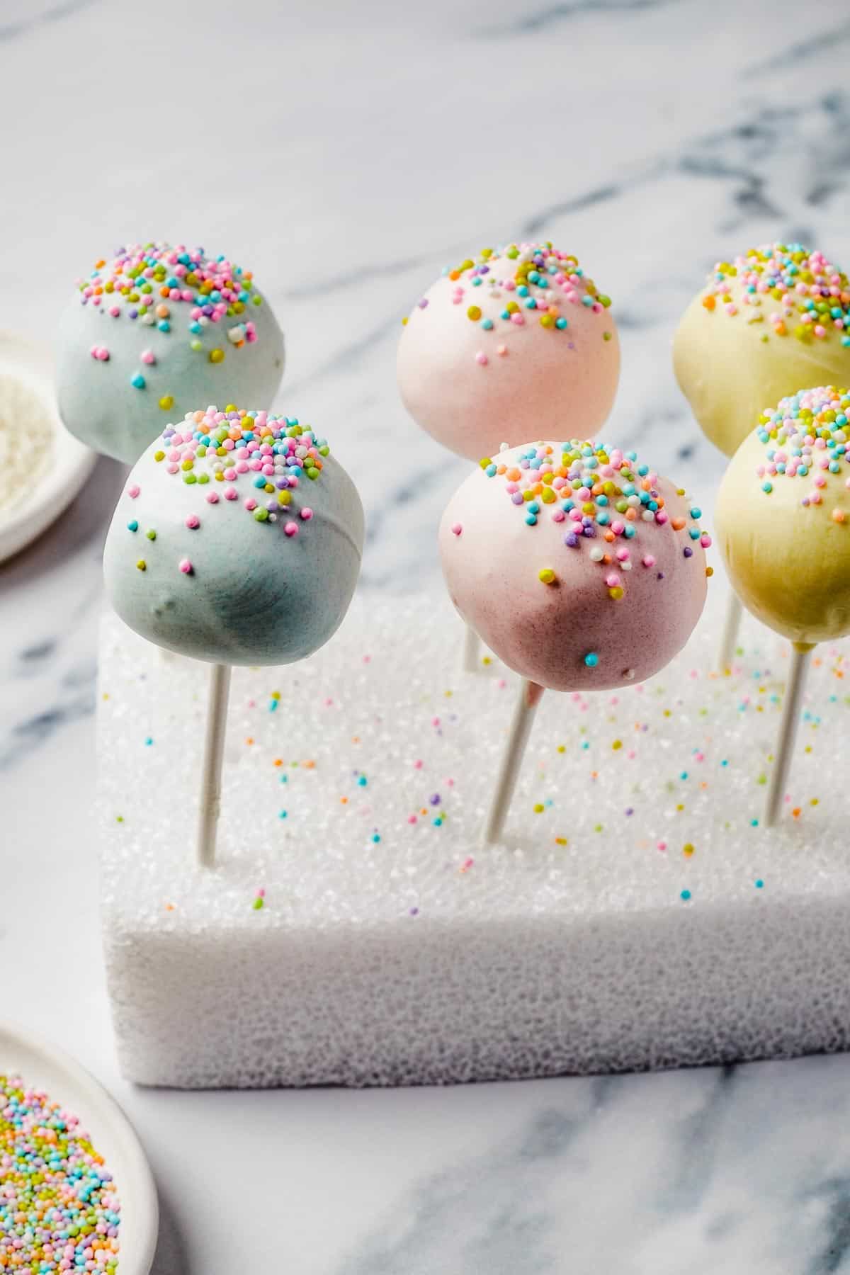 Lollipops cake pops with sprinkles, drying in a styrofoam block.