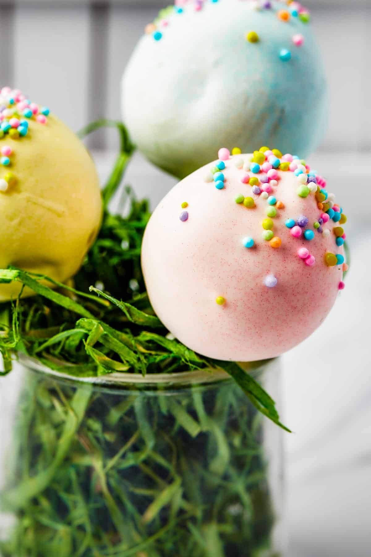 Pastel lollipops in a white basket filled with Easter grass.
