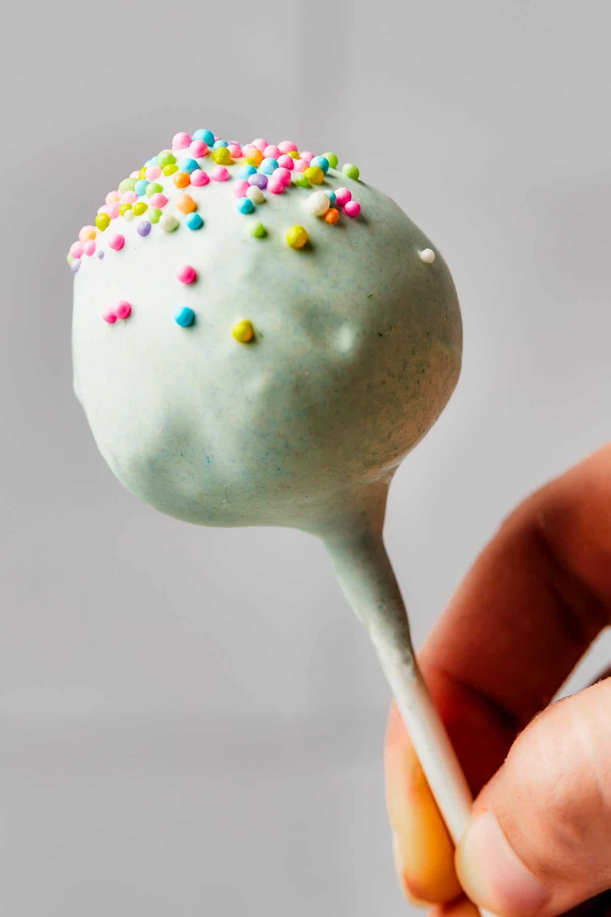 A pastel-colored cake pop with colorful sprinkles.
