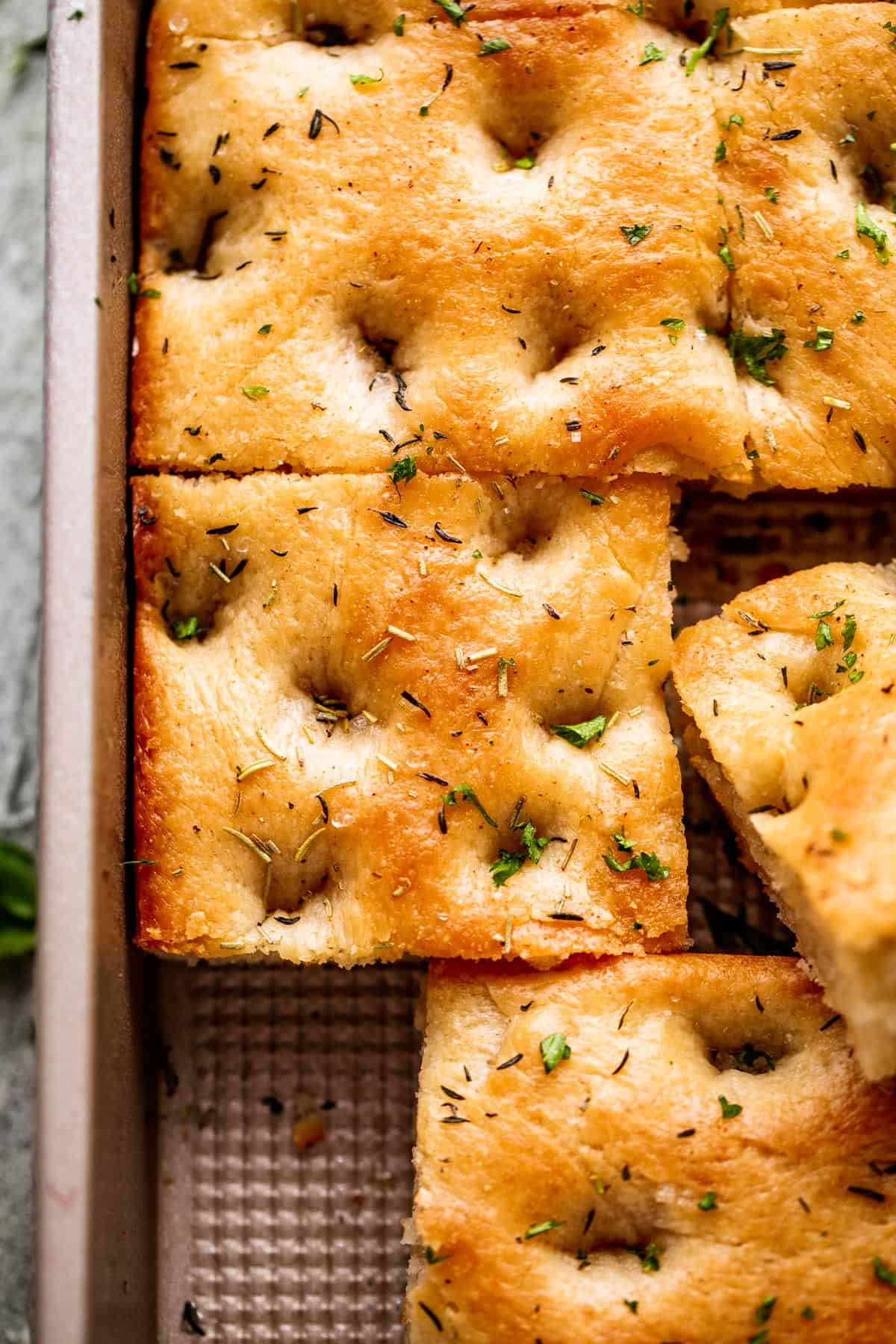 A large pan-sized loaf of focaccia, with one corner cut away.