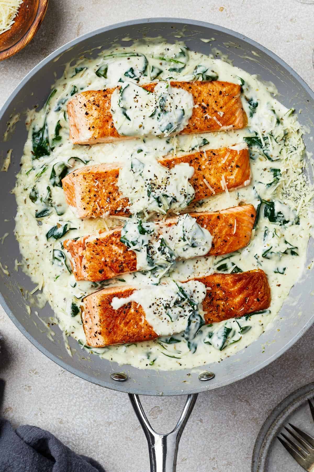 Salmon fillets in creamy spinach sauce in a gray nonstick skillet.