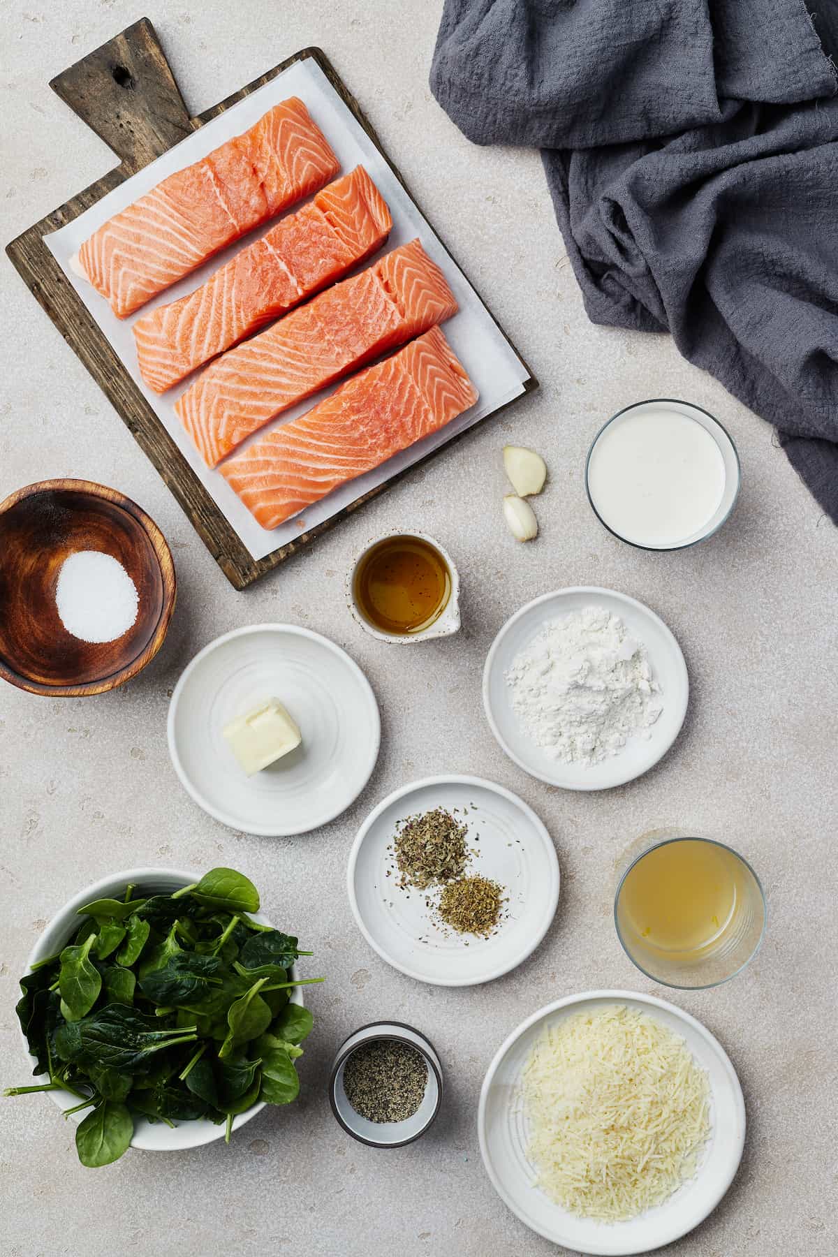 From top left: salmon fillets, garlic, heavy cream, salt, butter, olive oil, flour, dried herbs, chicken broth, spinach, pepper, Parmesan cheese