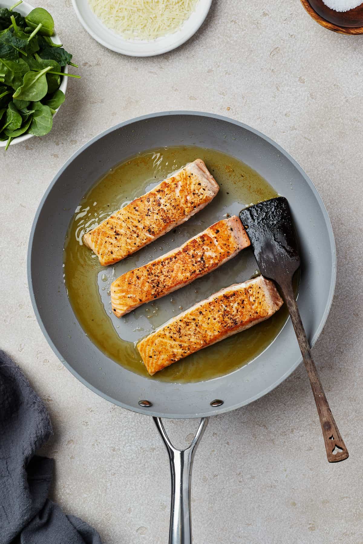 Salmon fillets cooking in a skillet.