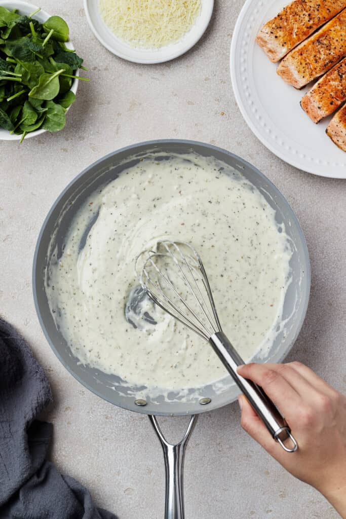 Creamy sauce being whisked in a skillet.