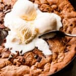 close up overhead shot of three vanilla ice cream scoops set on top of a large skillet cookie.